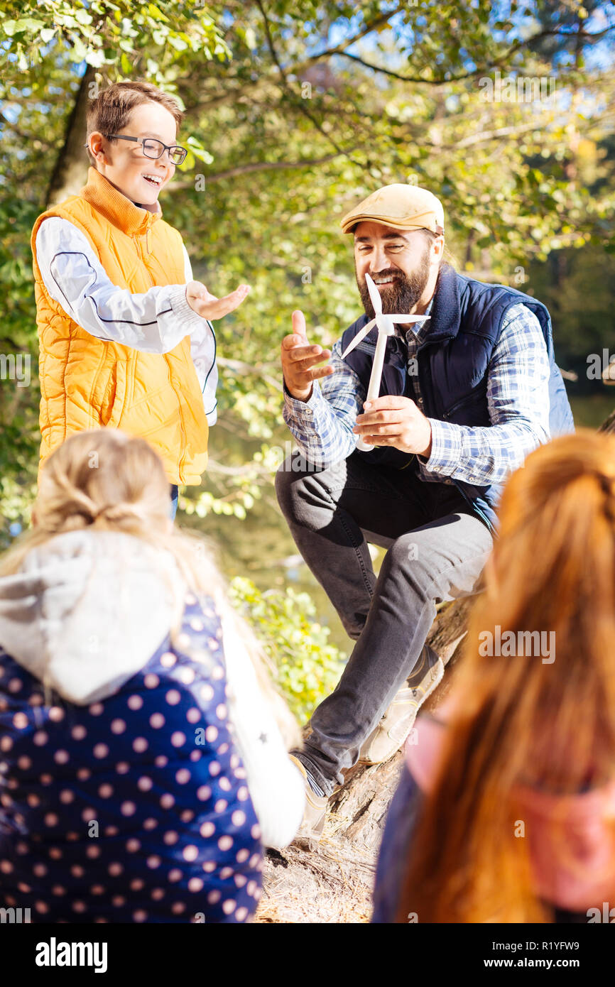 Allegro piacevole uomo che mostra un modello di mulino a vento Foto Stock