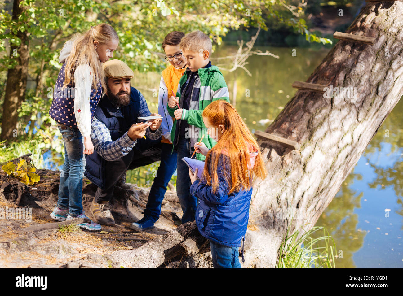 Positivo uomo barbuto che mostra una batteria solare modello Foto Stock