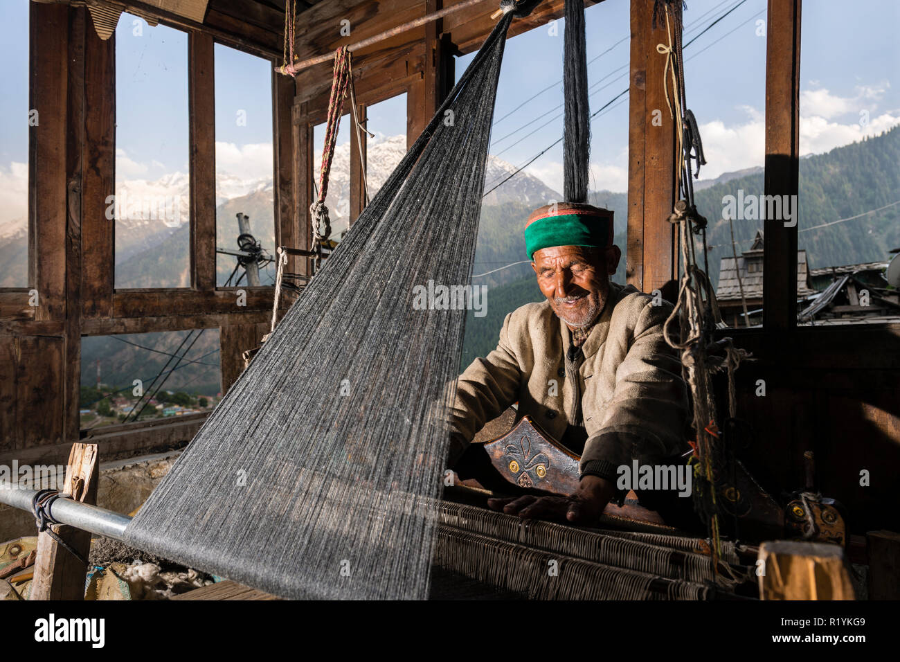 Un uomo locale tessitura a tessuti prodotti su telai a mano in Chitkul, l'ultimo villaggio della valle di Sangla Hill, situato a 3.400 m e circondato da montagne coperte di neve Foto Stock