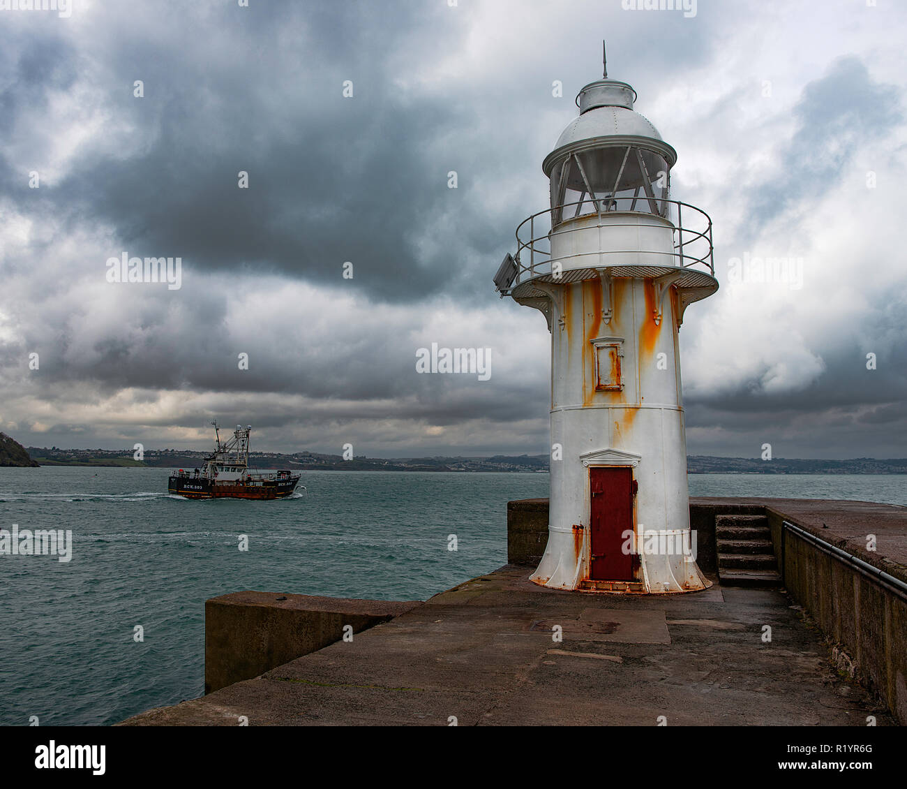 Pescherecci da traino con buttafuori lasciando Brixham harbour passato il faro. Foto Stock