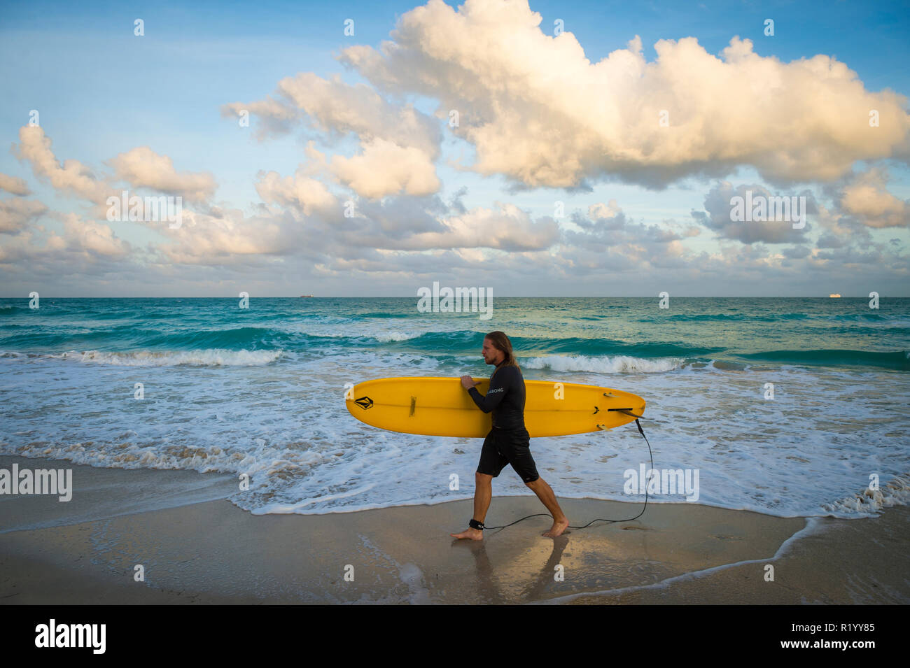 MIAMI - circa settembre, 2018: un giovane surfer passeggiate portando la sua longboard sulla spiaggia di South Beach. Foto Stock