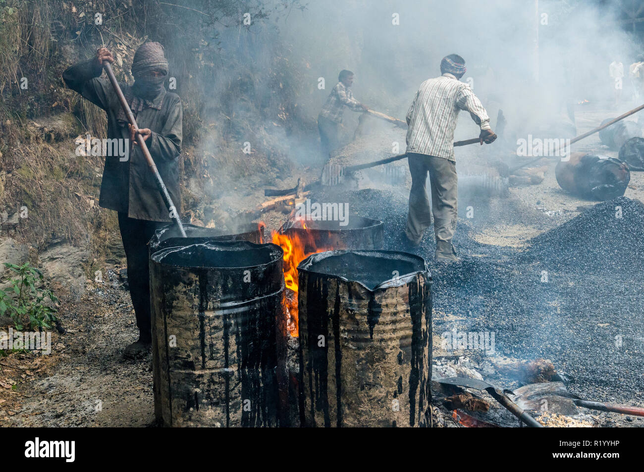 Strada in costruzione in India è principalmente svolto dalla manpower sotto molto insalubri condizioni. Il tar si riscalda fino a canne sul fuoco aperto Foto Stock