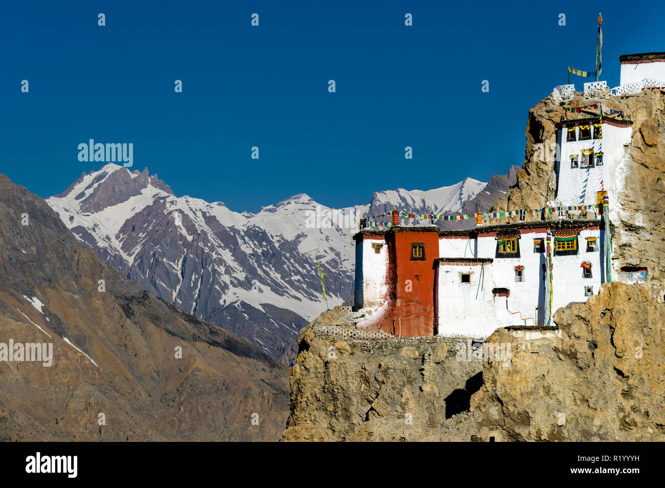 Il Gompa Dankhar, un tibetano monastero buddista, si trova in corrispondenza di una cresta rocciosa alta sopra la Spiti Valley. Montagne coperte di neve in background Foto Stock