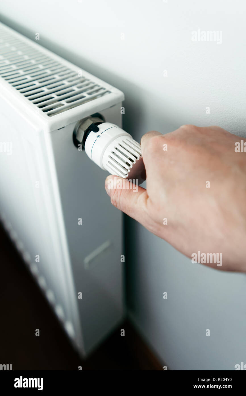 Gli uomini mano sulla batteria del controller di temperatura riscaldamento close up Foto Stock