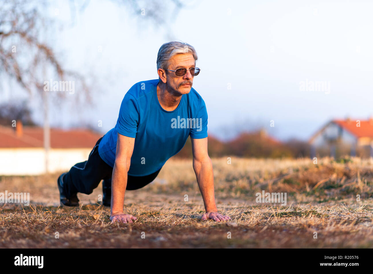 Senior uomo che fa pushups su un allenamento all'aperto Foto Stock