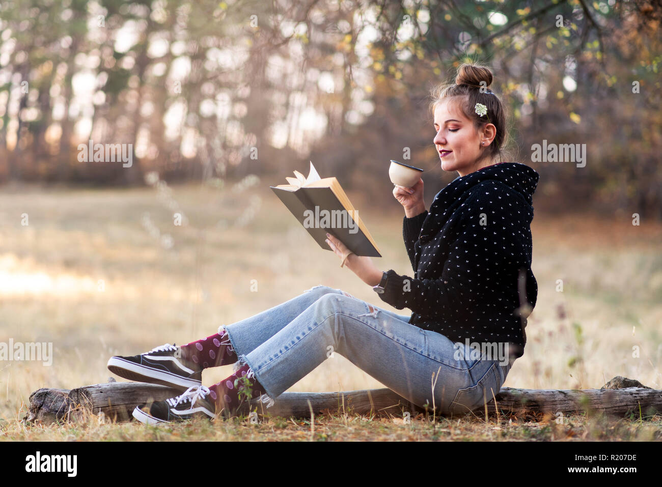 Ragazza la lettura di un libro e una tazza di caffè all'aperto Foto Stock
