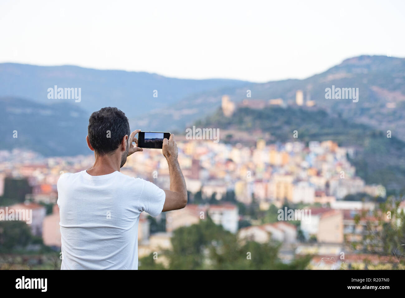 Un turista è di scattare una foto con il suo telefono cellulare al bello e colorato villaggio di Bosa si trova nel nord-ovest della Sardegna, Italia. Foto Stock