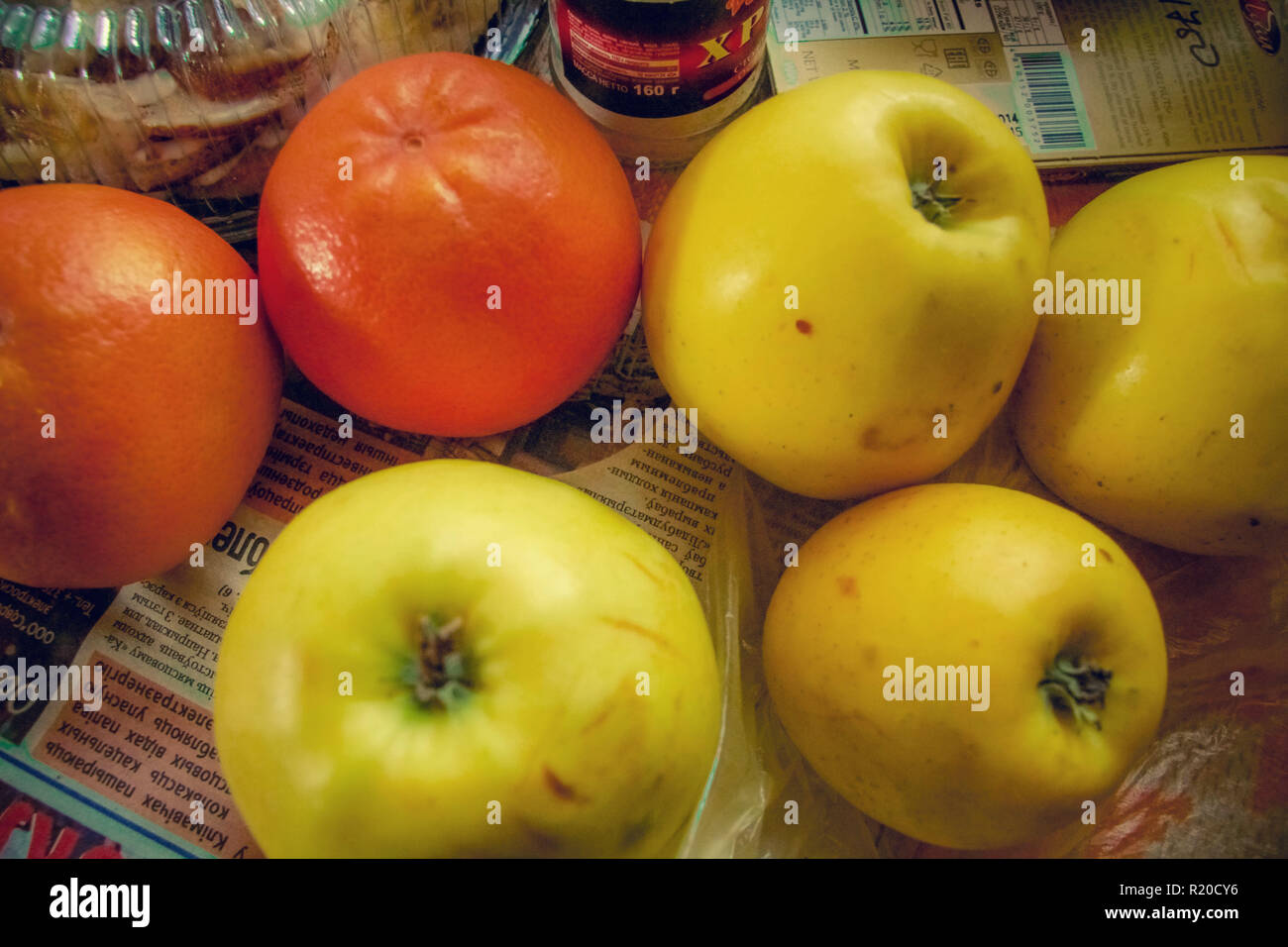 Mele e arance sul tavolo con il quotidiano. Foto Stock