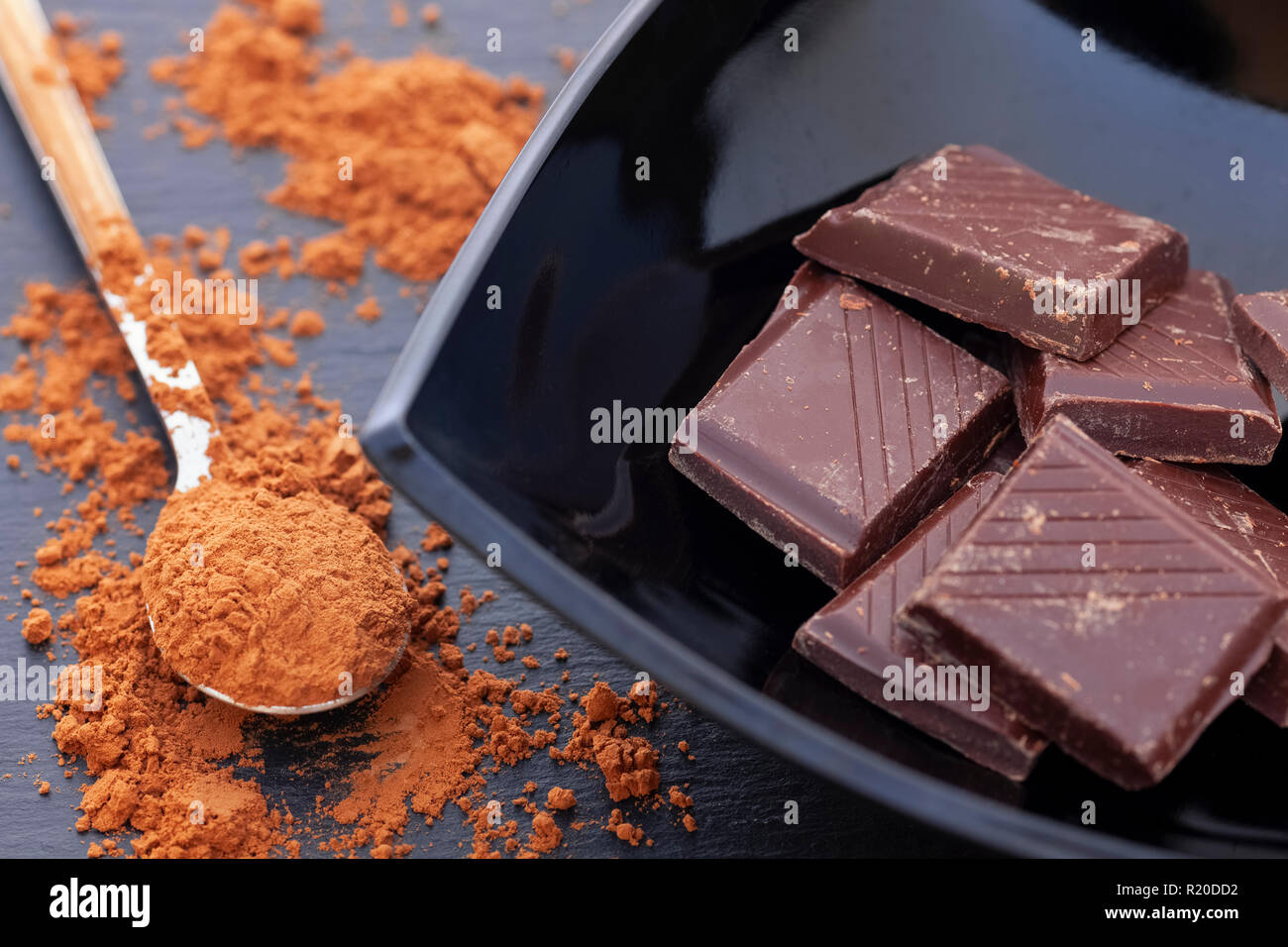 Rotto il cioccolato fondente in una ciotola nero e cacao in polvere. Close up. Foto Stock