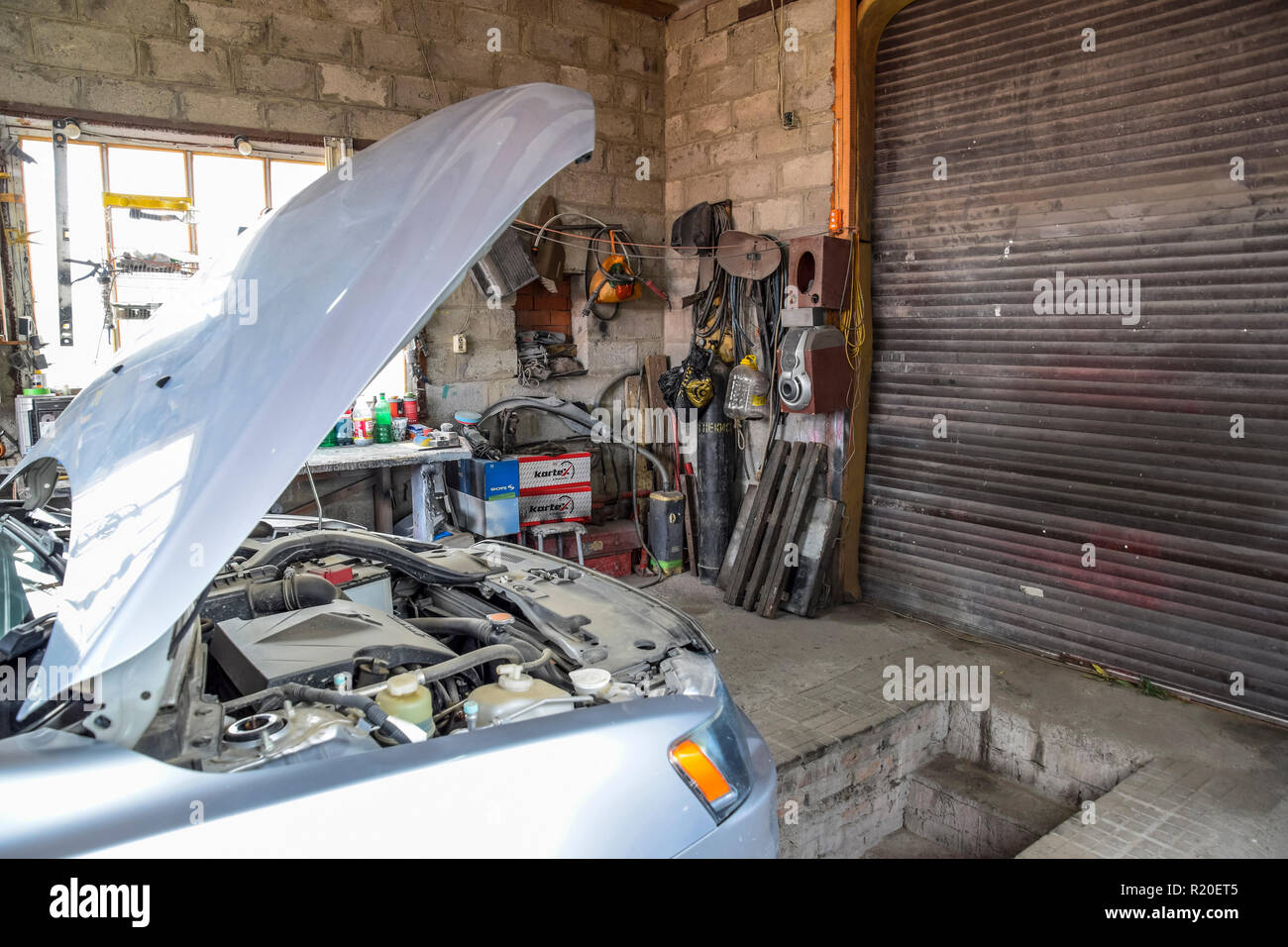 Una vettura con un cofano aperto nel garage. Strumenti e riparazione. Foto Stock