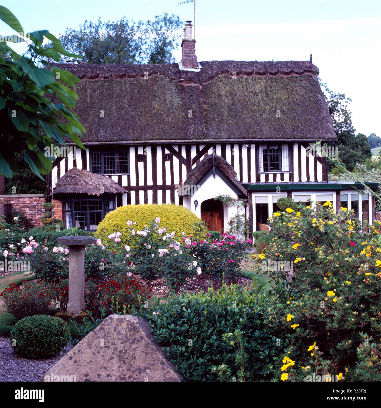 Esterno del nero+bianco casa in legno con il colorato giardino anteriore Foto Stock