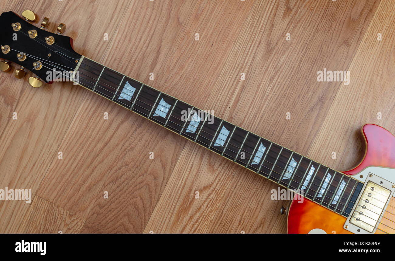 Chitarra elettrica. Vista dall'alto di una chitarra collo fretboard corpo e paletta contro il pavimento in legno sfondo, copia dello spazio. Foto Stock