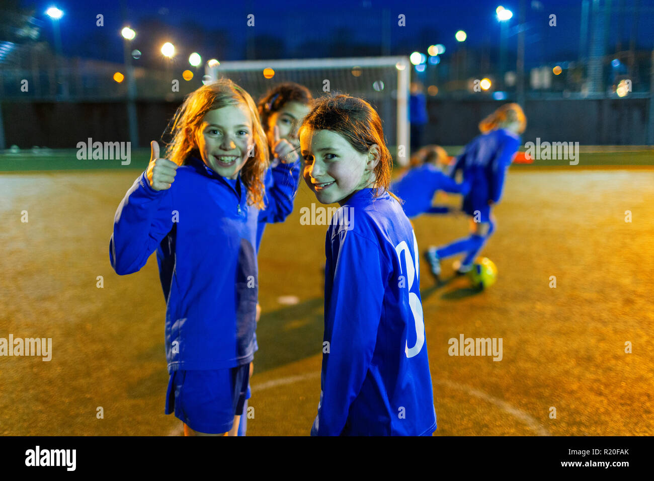 Ritratto fiducioso ragazza che gioca a calcio, gesticolando pollice in su Foto Stock