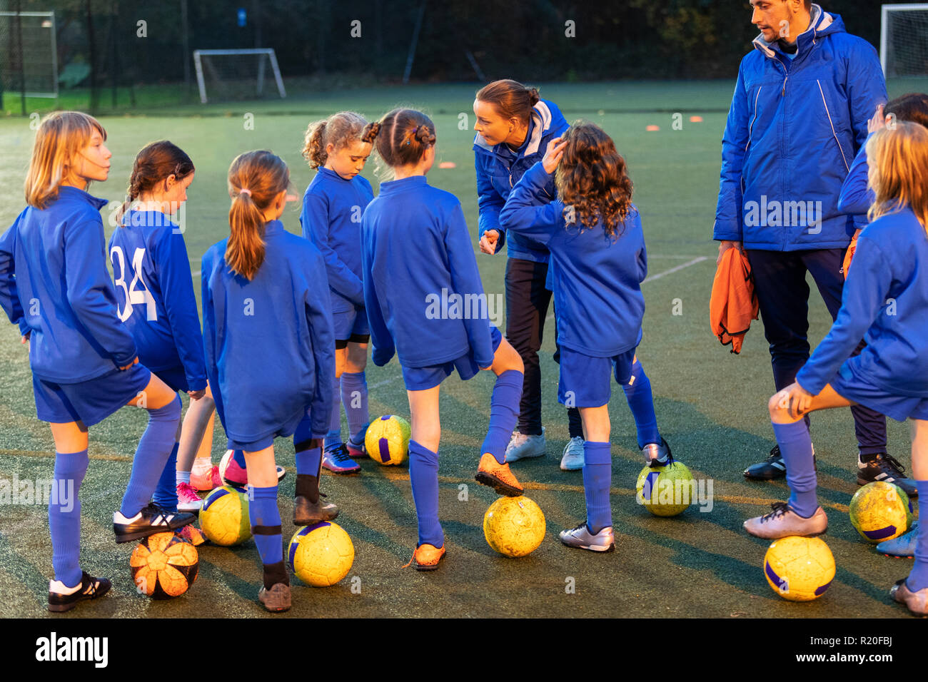 Ragazze Calcio team ascolto di allenatori sul campo Foto Stock