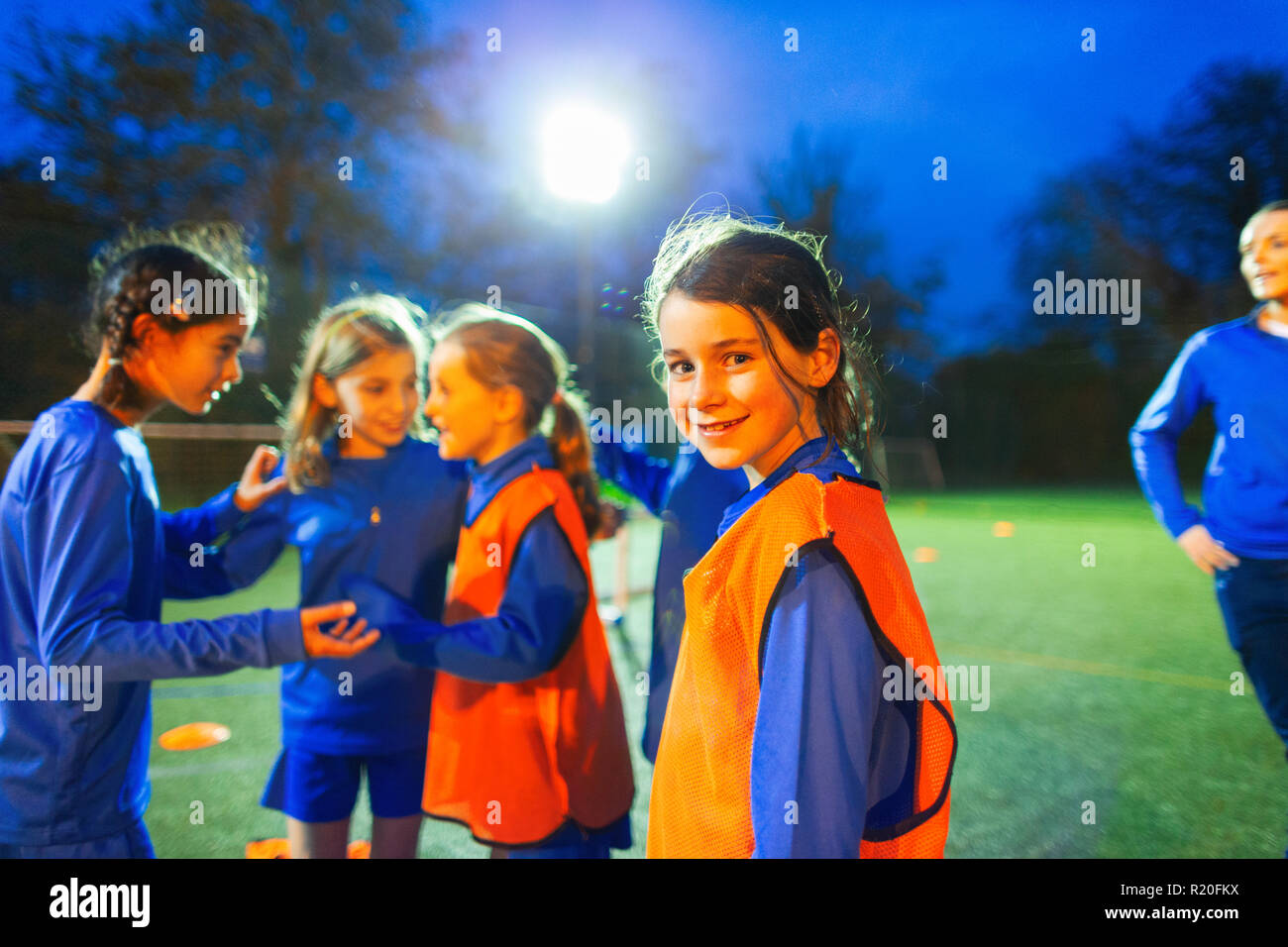 Ritratto fiducioso ragazza giocatore di calcio sul campo con il team di notte Foto Stock