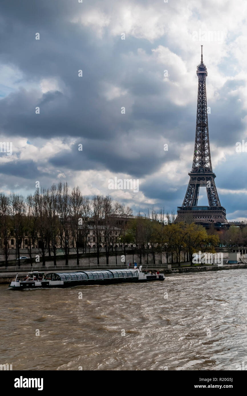 Bateau-mouche sulla Senna e vicino alla Torre Eiffel in un giorno con cielo drammatico, Parigi, Francia Foto Stock