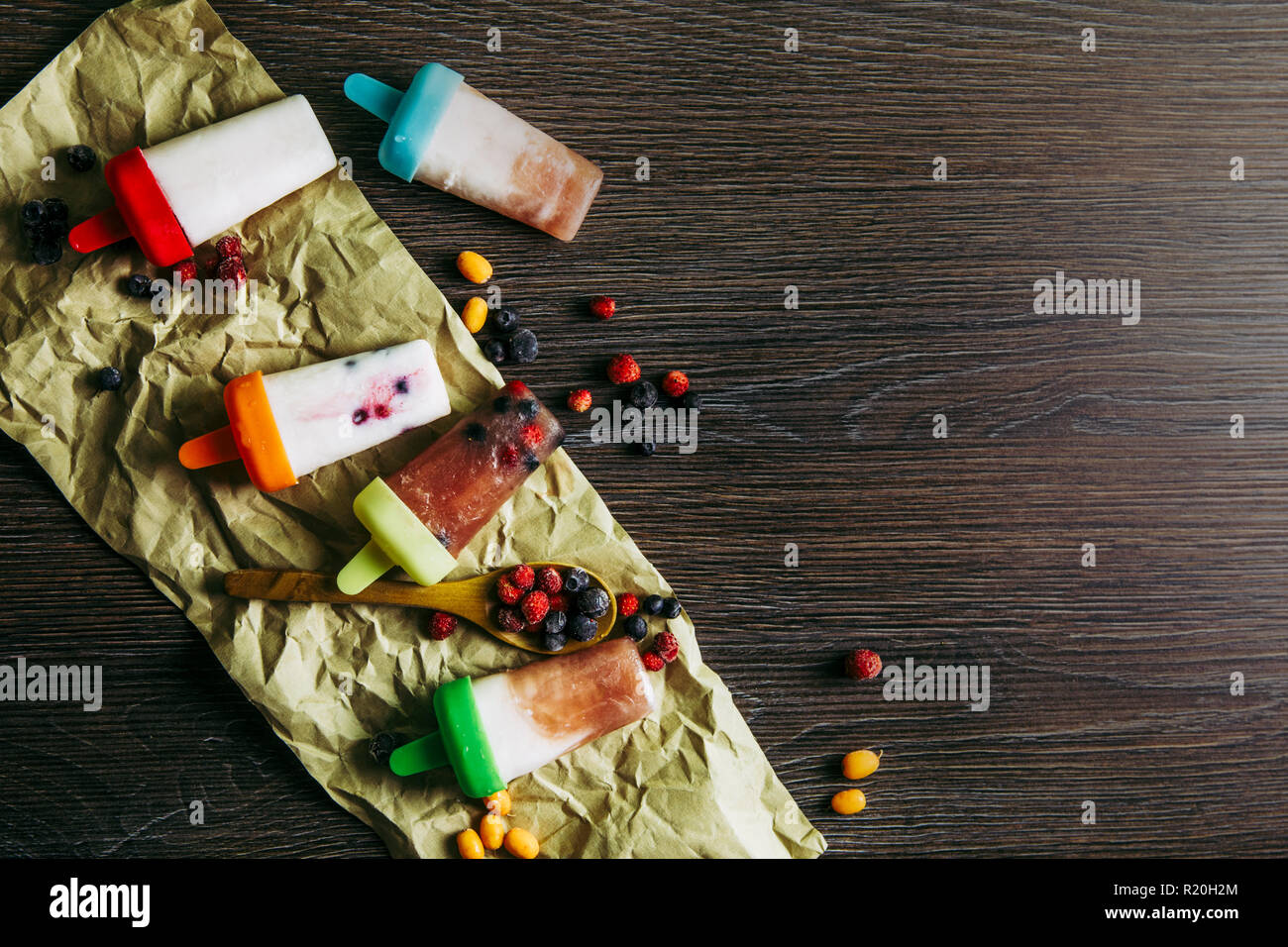 Appartamento vista laici del sacco di casa fatta frigo frullato congelati succhi yogurt gelato con frutti di bosco sul buio drammatico sfondo di legno. Snack sani c Foto Stock