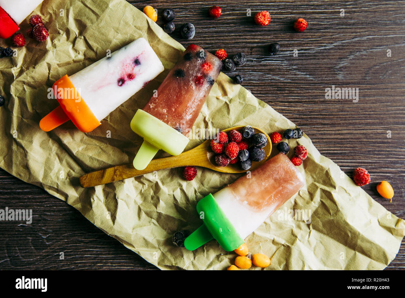 Appartamento vista laici del sacco di casa fatta frigo frullato congelati succhi yogurt gelato con frutti di bosco sul buio drammatico sfondo di legno. Snack sani c Foto Stock