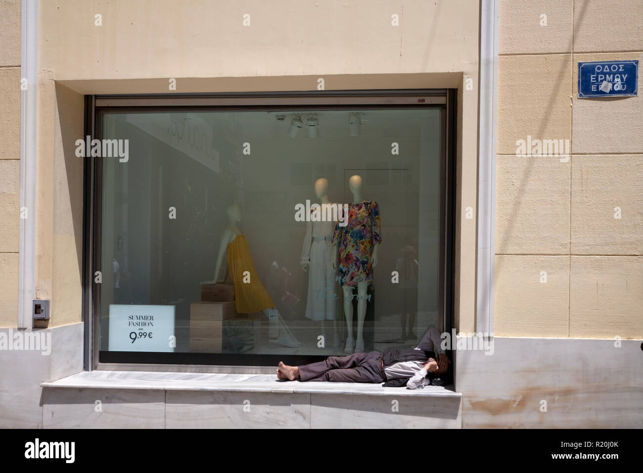 Fashion shop finestra e uomo addormentato nella parte anteriore della finestra ermou monastiraki Atene GRECIA Foto Stock