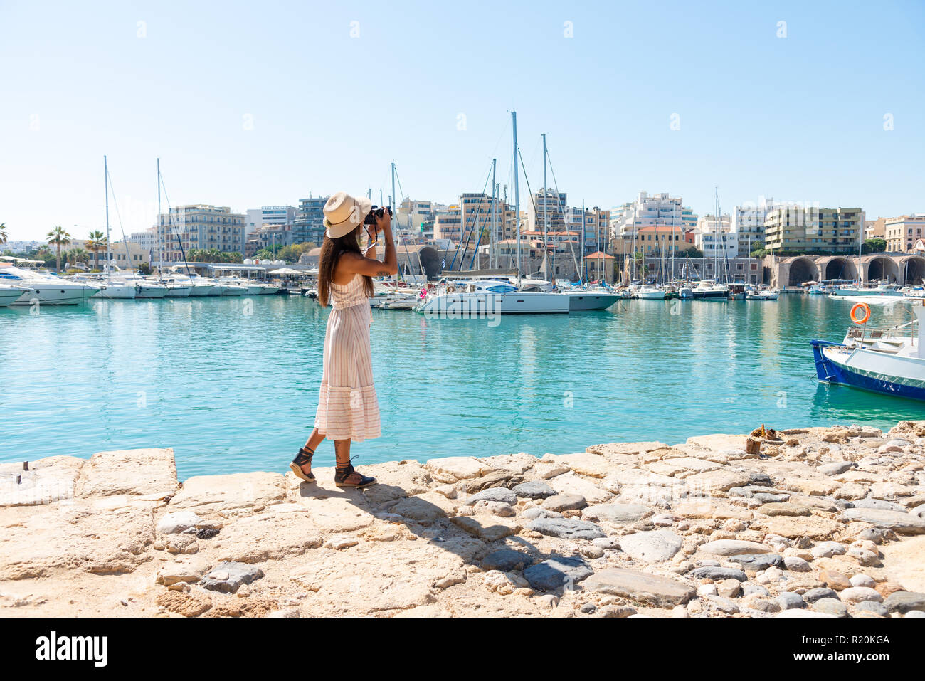 Viaggio donna turistica in vacanza a Heraklion Creta a piedi la porta.  Bella ragazza elegante in abito beige visitando la famosa Porta del  Mediterraneo Foto stock - Alamy