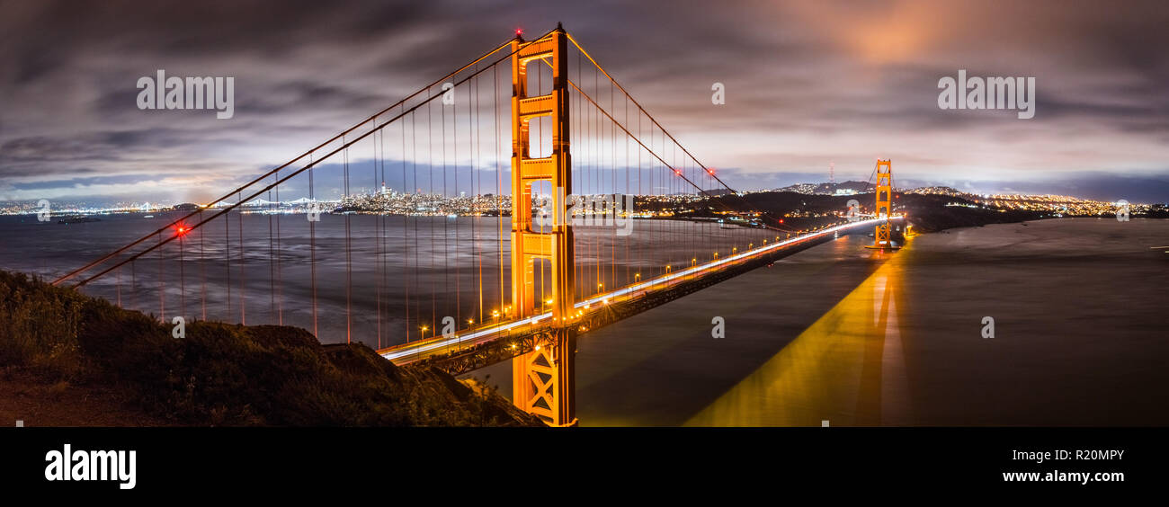 Panoramica vista notturna del Golden Gate Bridge di San Francisco Downtown area in background, California Foto Stock