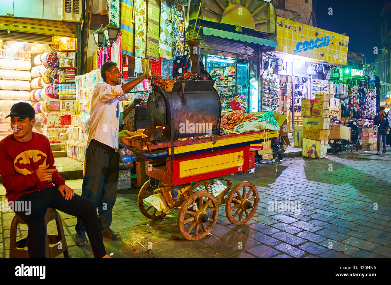 Il Cairo, Egitto - 21 dicembre 2017: il venditore ambulante di patate dolci cuochi batata nel forno, in piedi sul suo food cart in Al Muizz street del Vecchio Bazar, Foto Stock