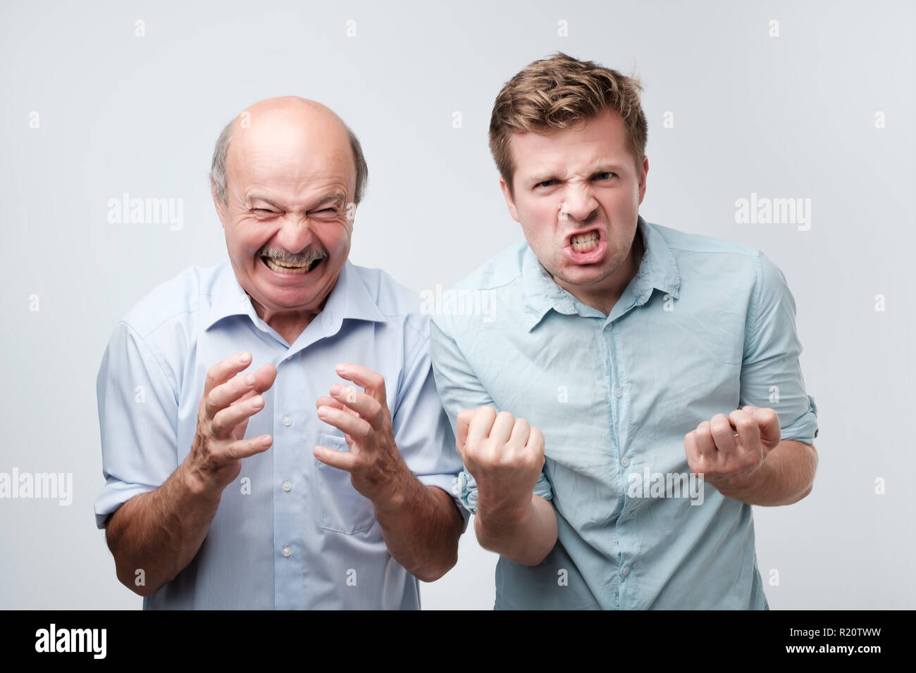 Furious arrabbiato due uomini esclamare con emozioni negative gridare a gran voce, oltre studio bianco parete. Irritato il figlio e il padre hanno mancato Foto Stock
