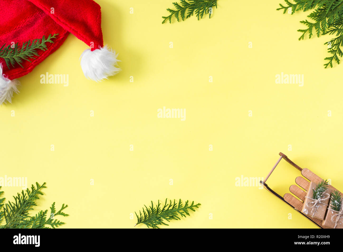 Moderno banner di Natale con Babbo Natale hat, albero di natale e confezioni regalo su giallo pastello. sfondo Xmas concetto creativo. Foto Stock