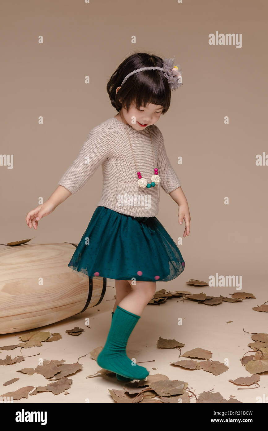 Poco bella ragazza asiatica seduto in un autunno sfondo. Foto Stock