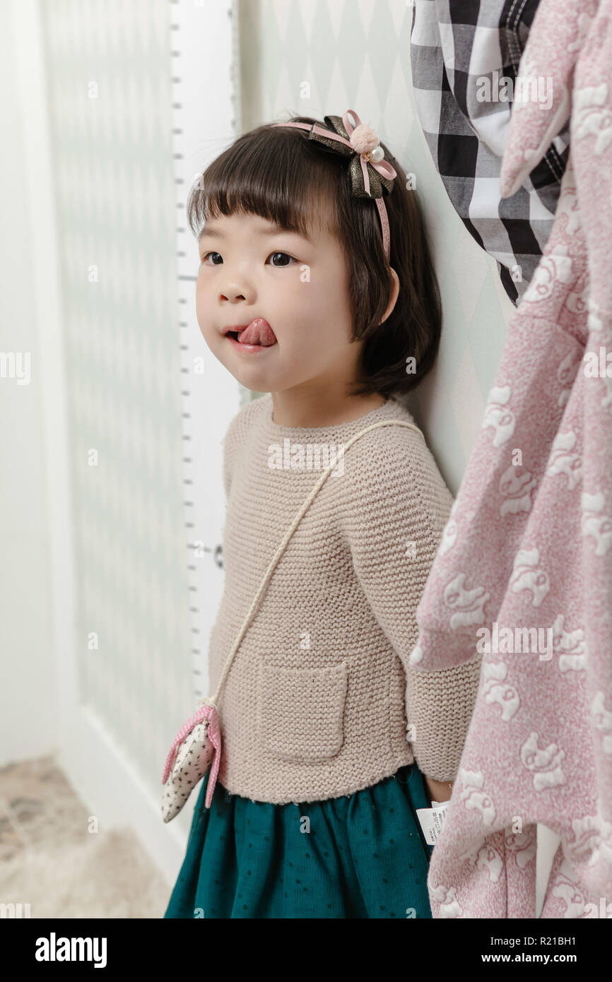 Poco bella ragazza asiatica in piedi in una normale vita interna dello sfondo. Foto Stock
