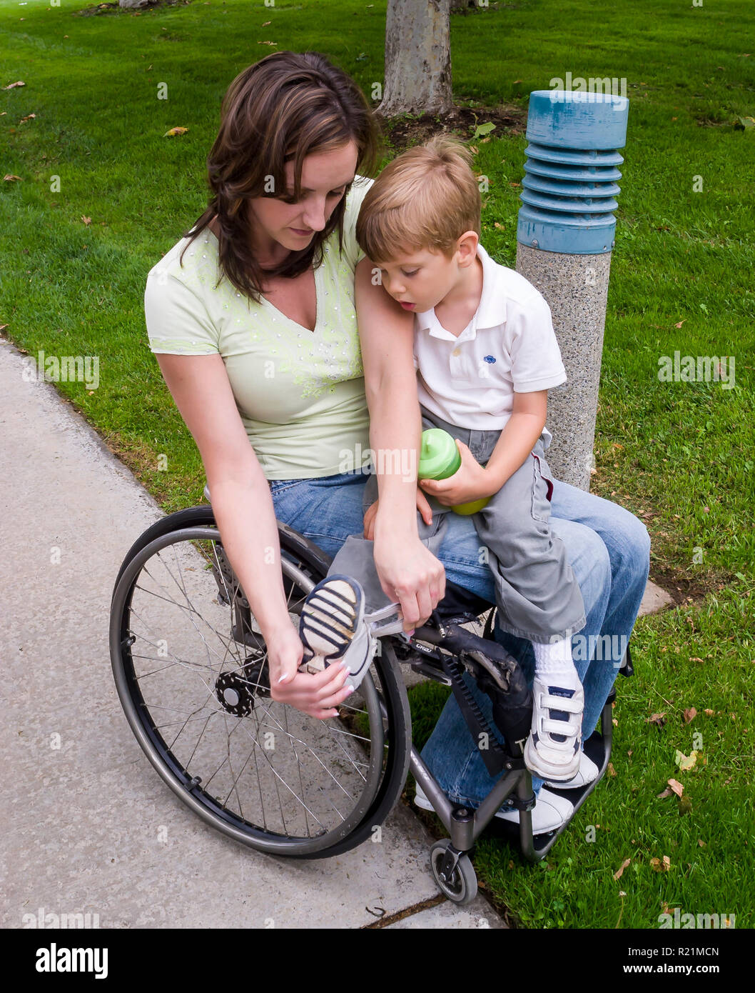 Mom disabili in carrozzella aiuta le piccole boy mettere sulla calzatura. © Myrleen Pearson ......Ferguson Cate Foto Stock