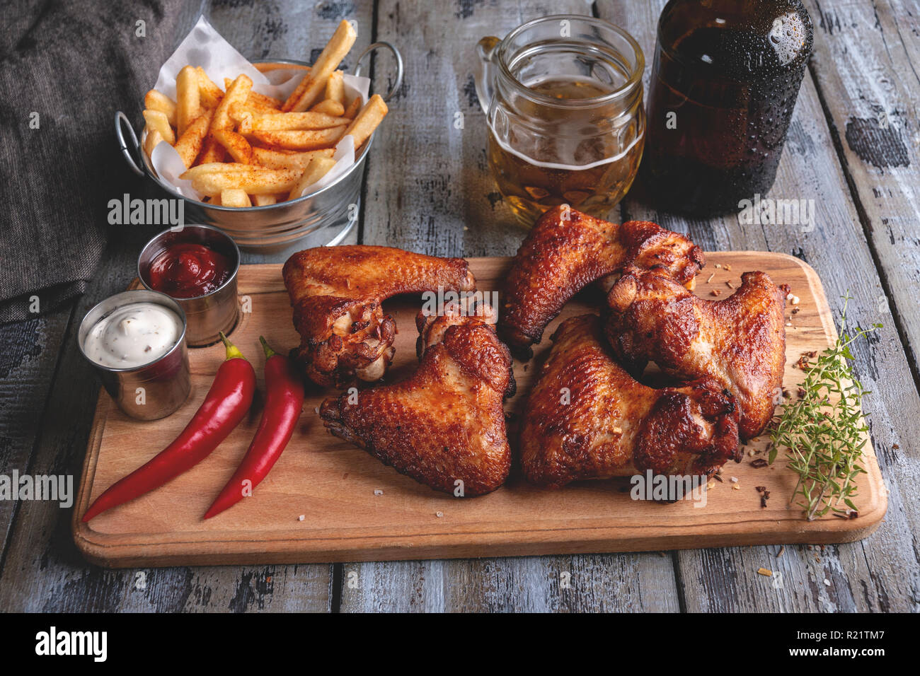 Grigliata di ali di pollo e patatine fritte, bianco e salsa rossa. La birra snack Foto Stock