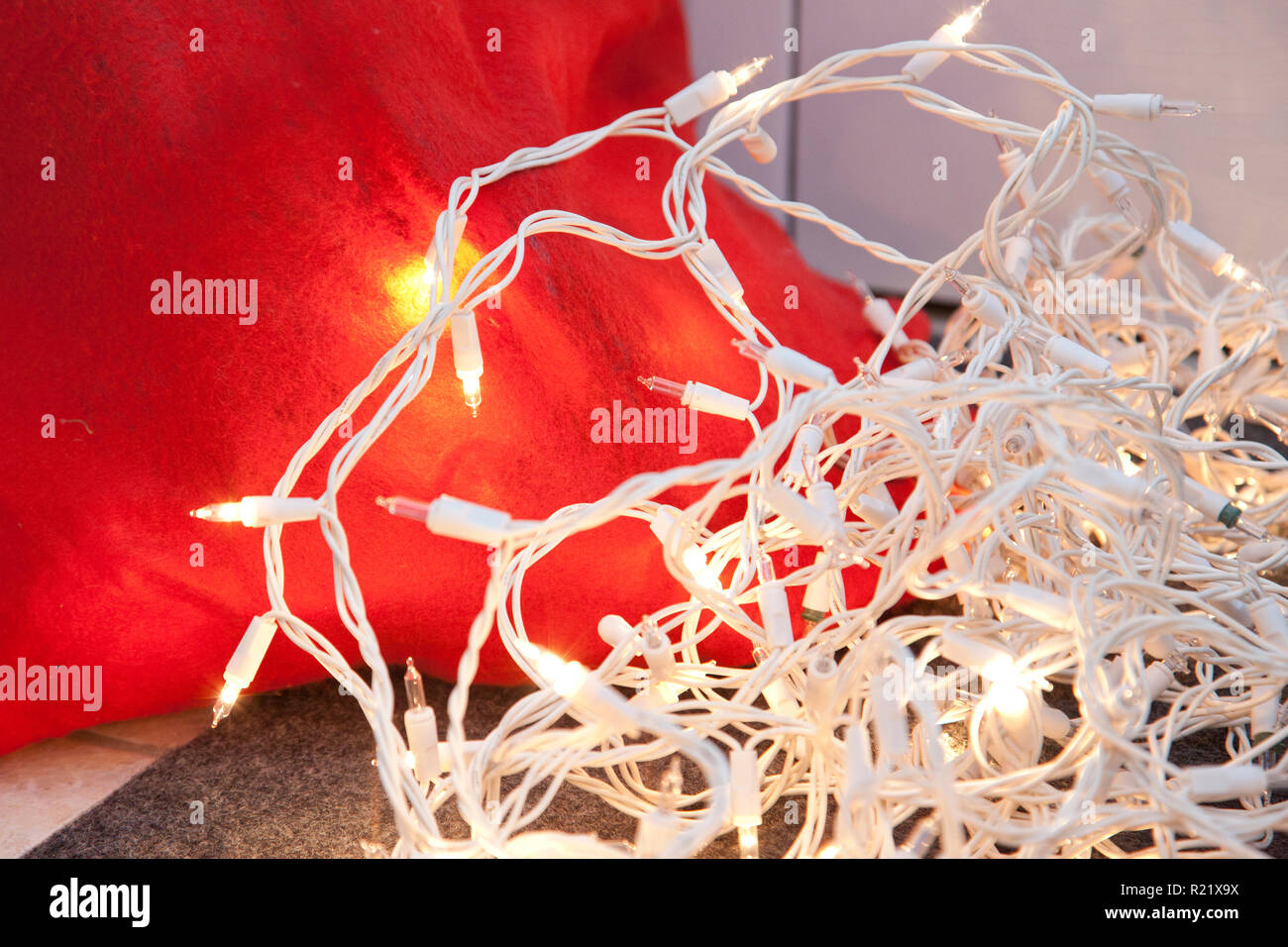 Un fascio bianco delle luci delle vacanze, accanto a un rosso santa in borsa Foto Stock