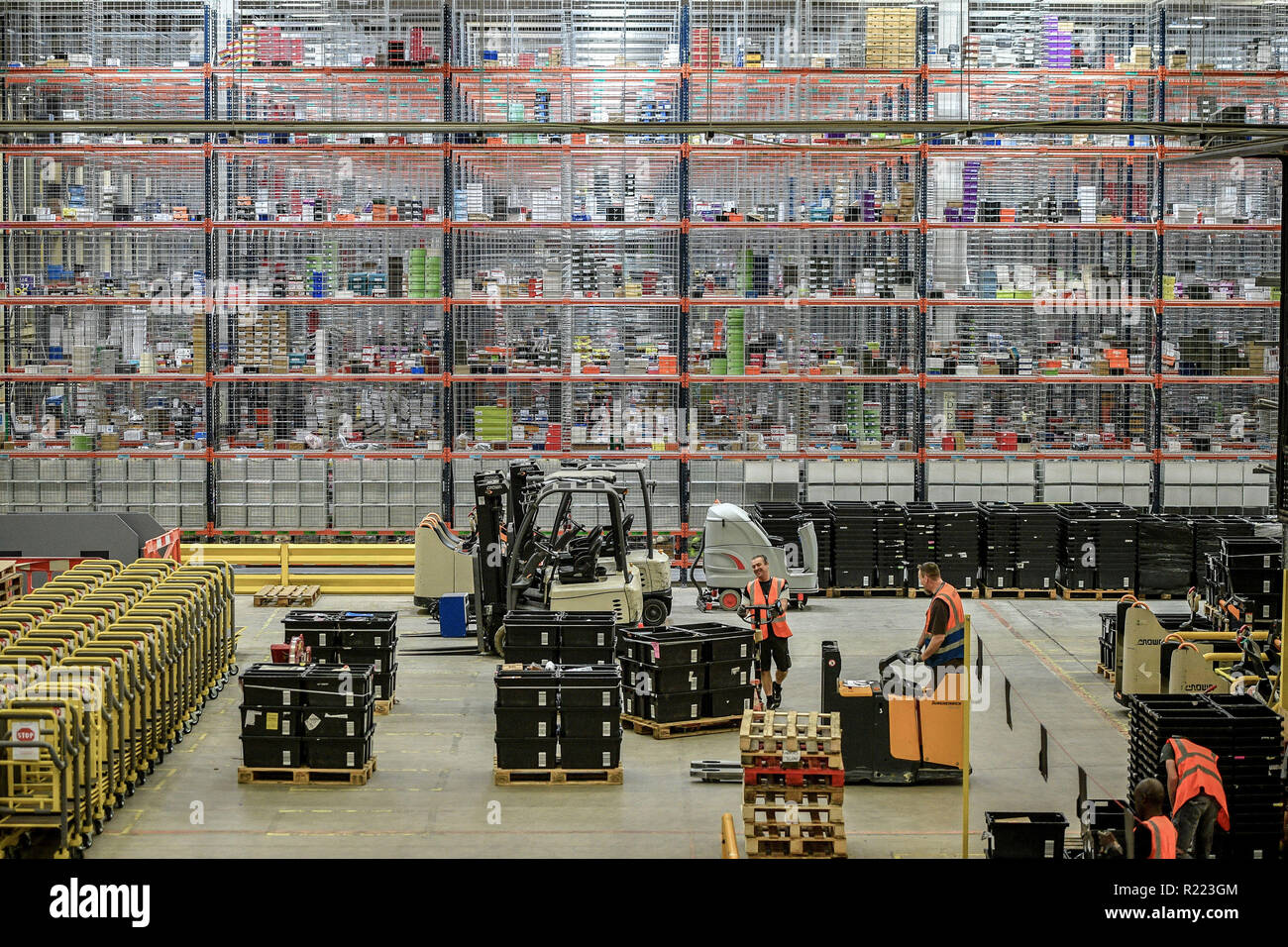 I lavoratori si muovono carrelli nella parte anteriore del rack enorme contenente migliaia di articoli presso Amazon Fulfillment nel centro di Swansea, nella corsa fino a venerdì nero. Foto Stock