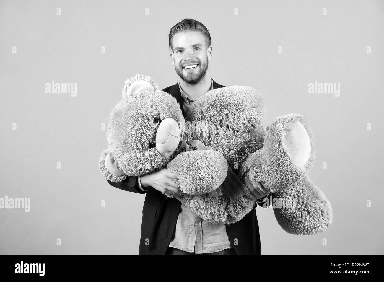 Macho sorriso con il grigio Teddy bear. Uomo felice grosso animale giocattolo. Uomo sorridente con il grosso animale giocattolo. Dono e il presente concetto. Moda e stile. Compleanno o anniversario e vacanze celebrazione. Foto Stock