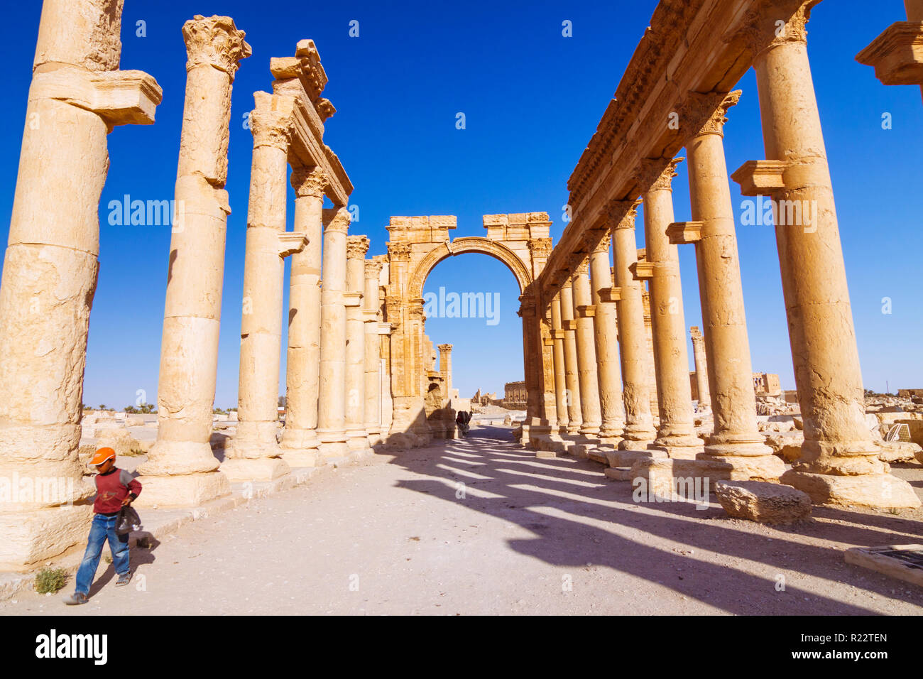 Palmyra, Homs Governatorato, Siria - Maggio 27th, 2009 : un bambino passeggiate lungo il grande colonnato e III secolo monumentale arco di trionfo di Palmyra, un Foto Stock