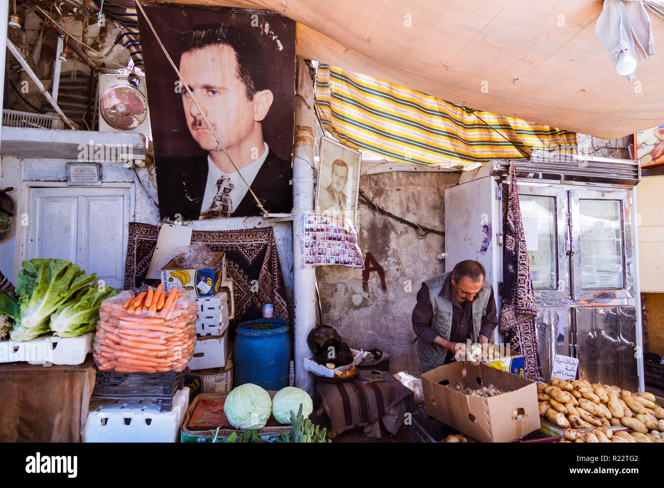 Damasco, Siria, 29 Maggio 2009 : un distributore vende verdure a una pressione di stallo di mercato dominato da un grande ritratto del presidente della Siria Bashar al-Assad. Foto Stock