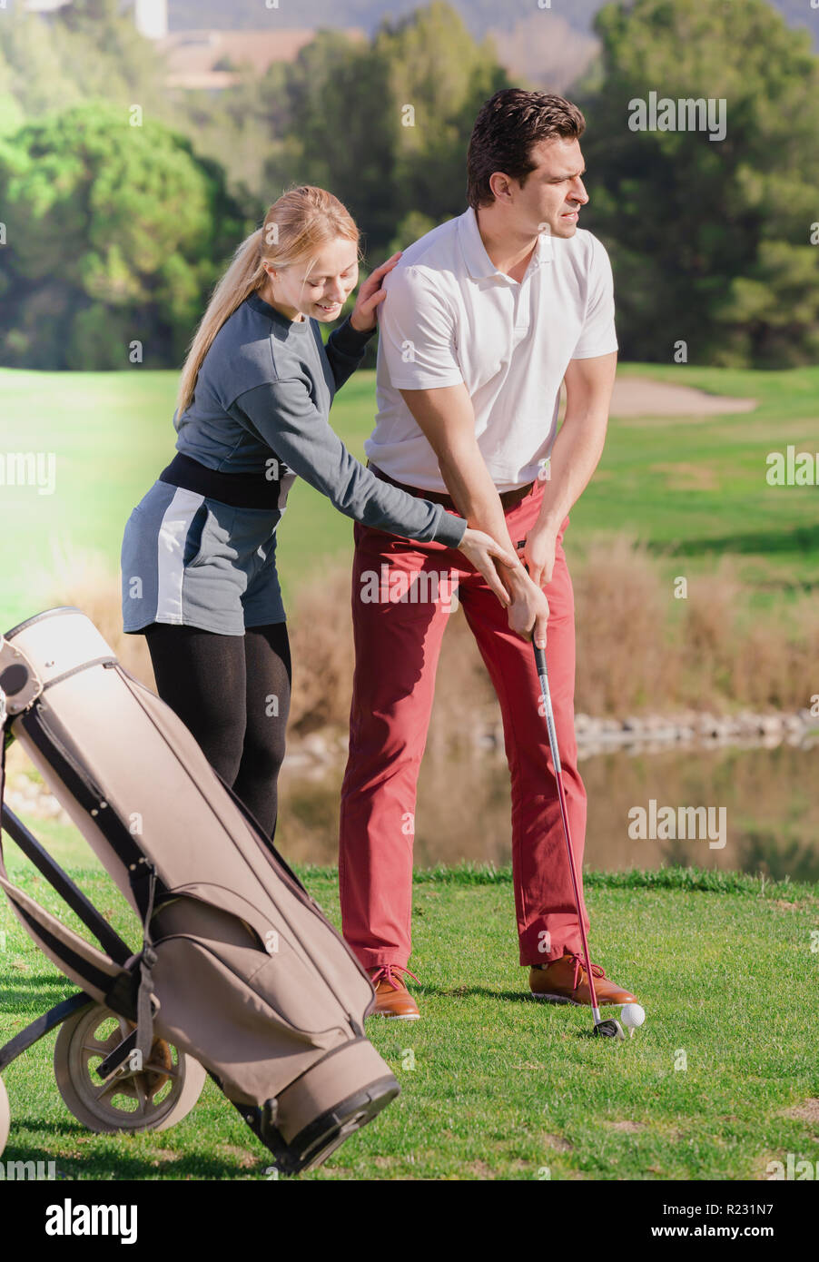 Sorridente golf trainer che mostra il lettore maschio come colpire giustamente a sfera Foto Stock