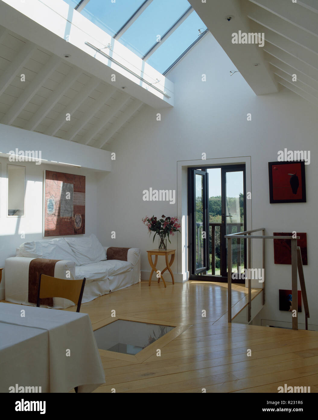 Divano bianco in grande piano aperto spazio soggiorno con pavimento in legno Foto Stock