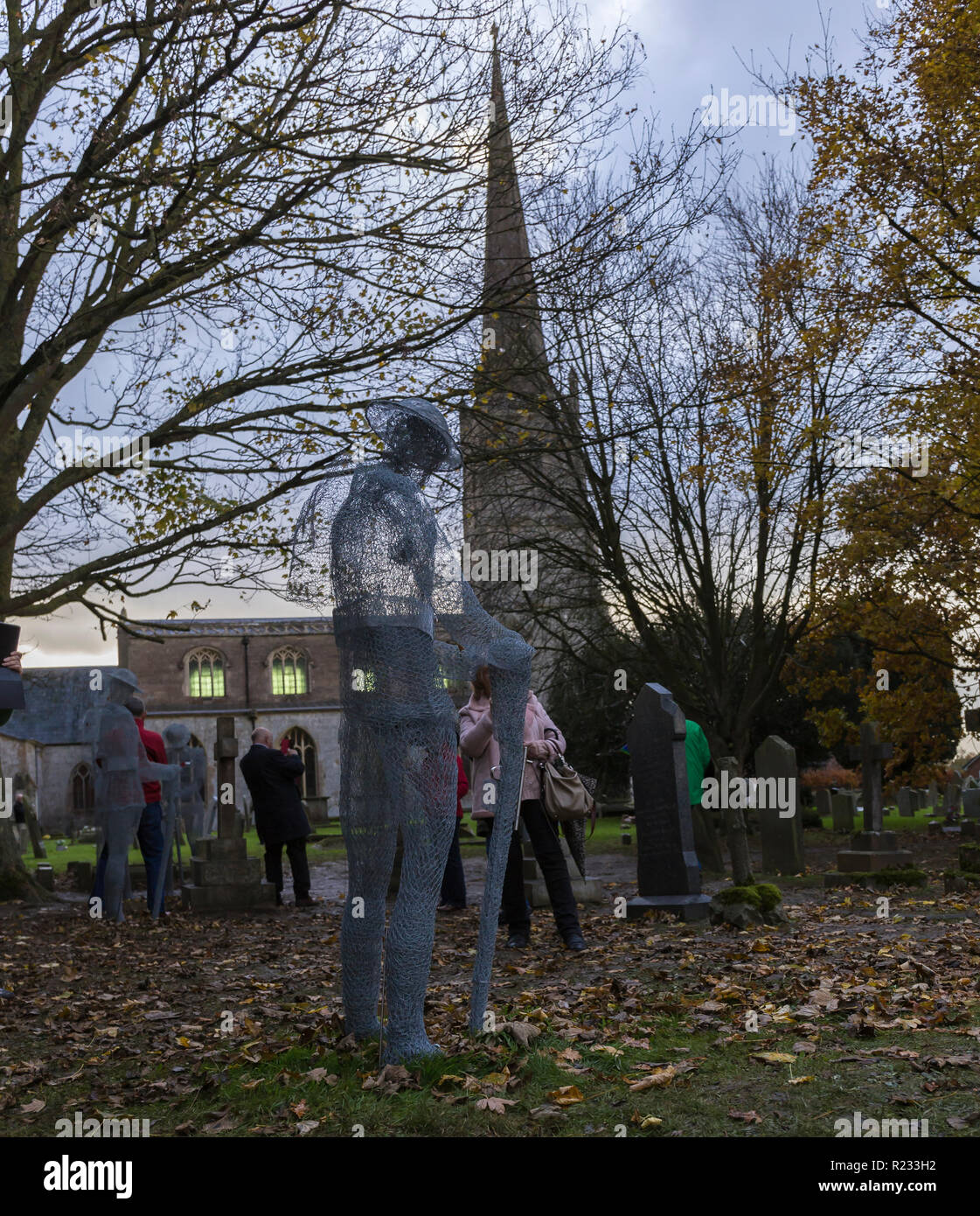 "Ghostlike' sculture (dall artista Jackie Lantelli) di soldati morti nella guerra mondiale uno accanto alle loro tombe nel cimitero di Slimbridge Foto Stock