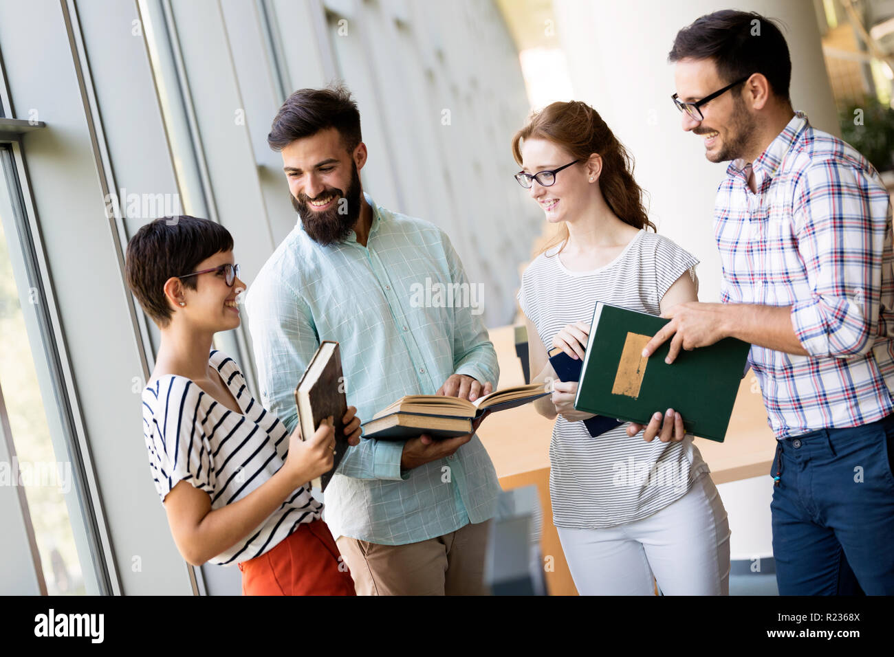 Contenti i giovani studenti universitari che studiano con libri in biblioteca Foto Stock