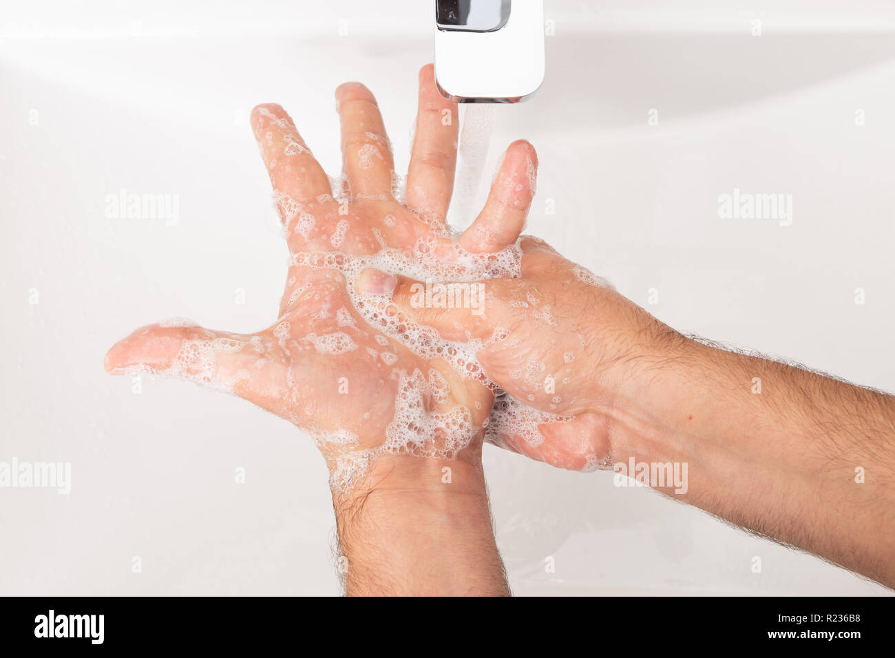 Close-up di uomo che pulisce le mani sotto acqua come igiene personale concetto Foto Stock