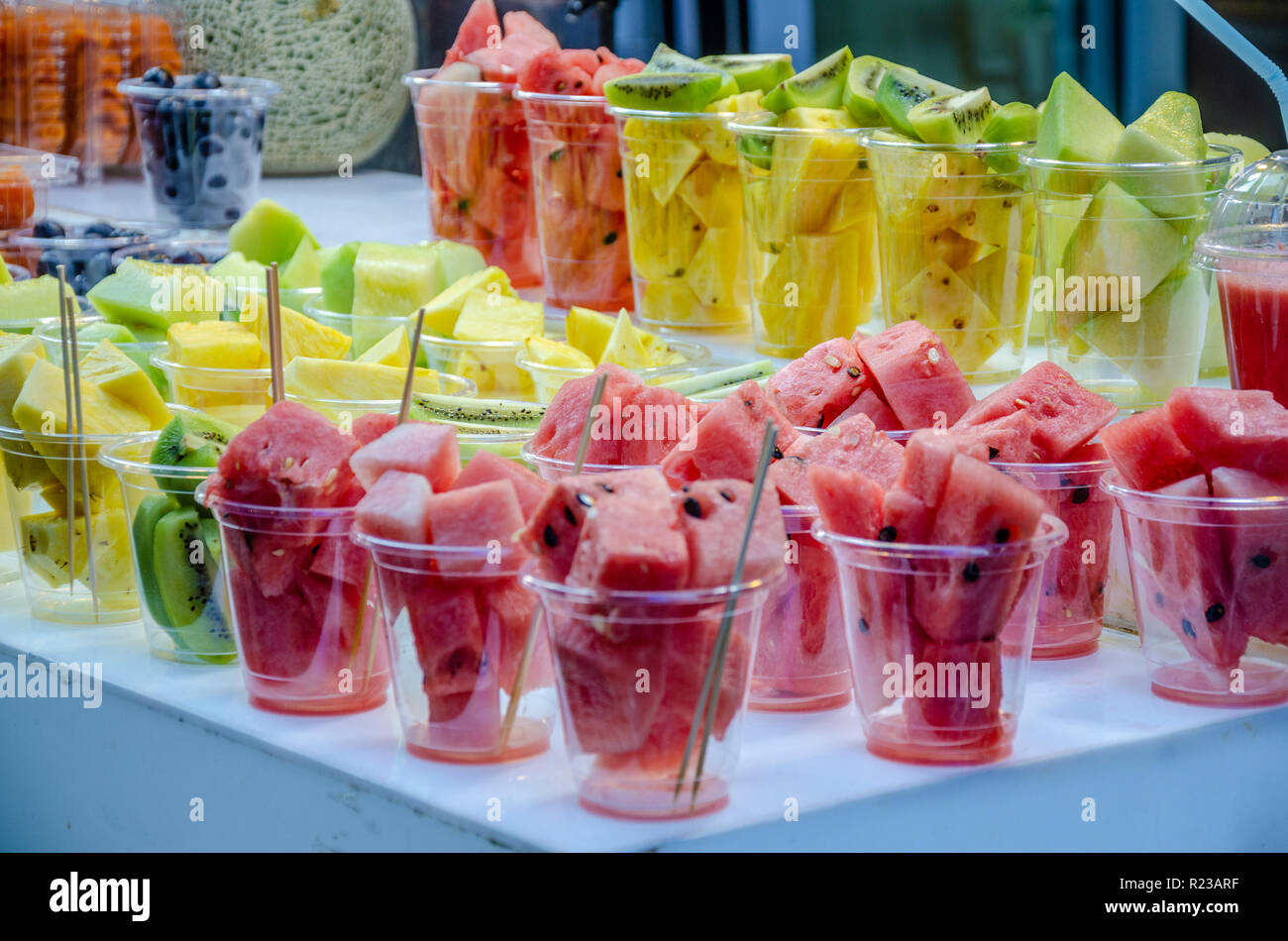 Bicchieri di plastica di trito di frutta, anguria, kiwi e ananas pronto a fondersi in un succo di frutta sulla visualizzazione in un mercato alimentare di strada in stallo. Foto Stock