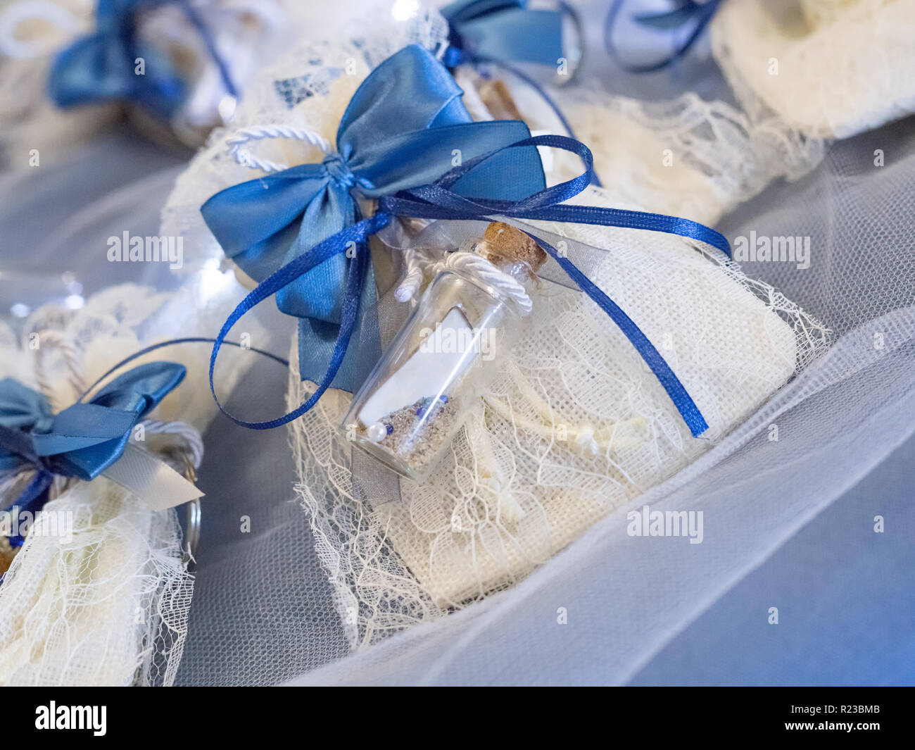 Bomboniera decorata con pizzo e nastro di colore blu con un messaggio in bottiglia con etichette bianche pronti a personalizzare con il vostro testo Foto Stock