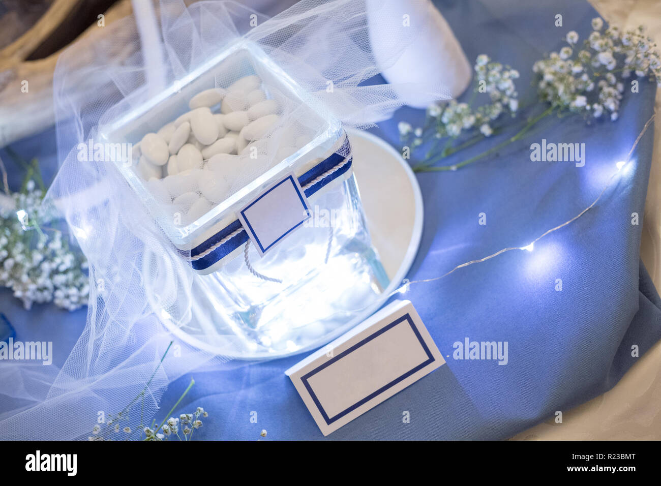 Vaso illuminato con i confetti con white label per personalizzare l'immagine, la corda per la decorazione e il cono per confetti sul tavolo blu. Foto Stock