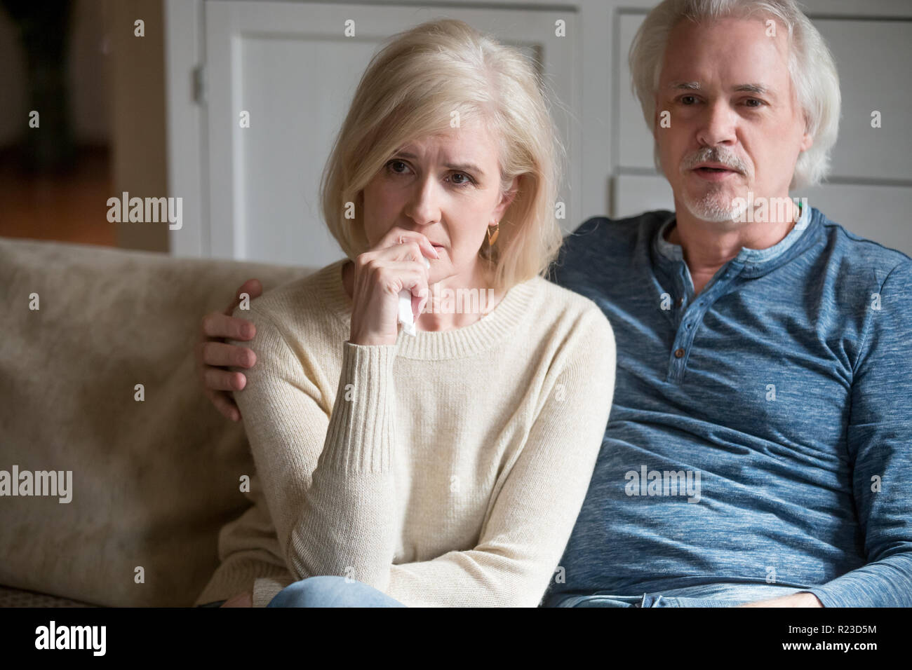 Senior emozionale il marito e la moglie guarda triste film rilassarsi su comodi divani a casa, sensibile di età matura trascorrere weekend insieme godendo di serie di dramma o Foto Stock