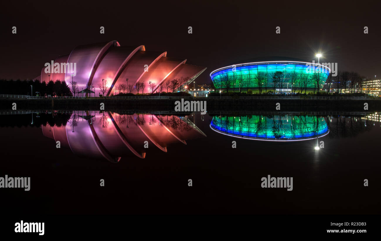 Glasgow, Scotland, Regno Unito - 4 Novembre 2018: Il modernista SEC Armadillo auditorium e SSE idro arena sono illuminate di notte e si riflette nel fiume Clyde Foto Stock