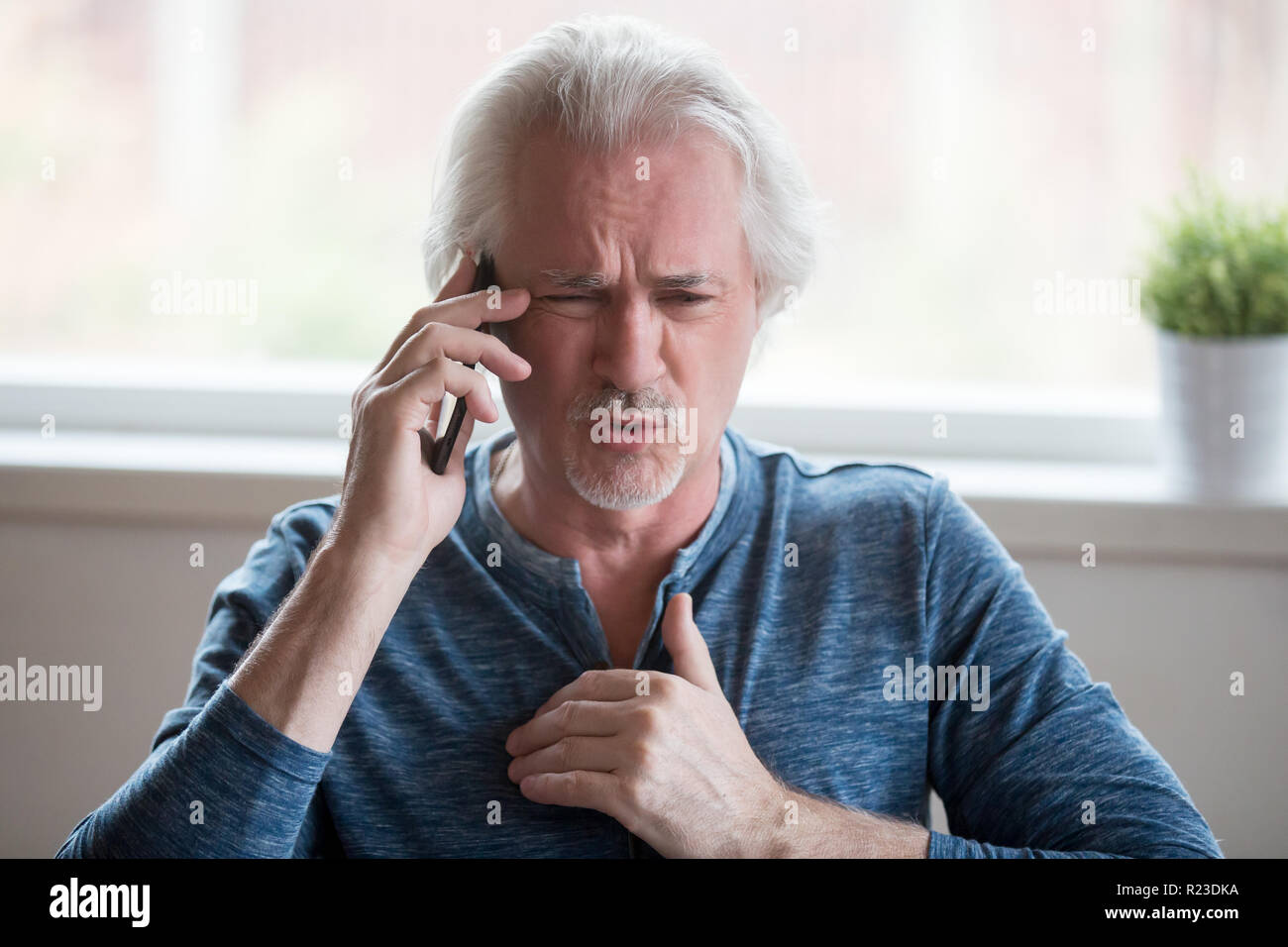 Arrabbiato uomo più anziano talk su cellulare sostenendo o avente controversia con un'altra persona, determinato maschio senior dimostrare il punto di vista coinvolti nel discutere del telefono Foto Stock