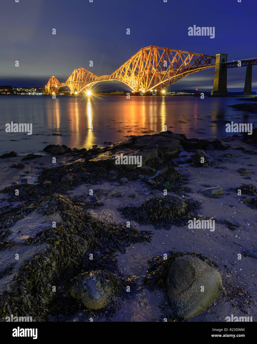 Il Forth Bridge è illuminata al tramonto del Firth of Forth a South Queensferry a Edimburgo, Scozia. Foto Stock