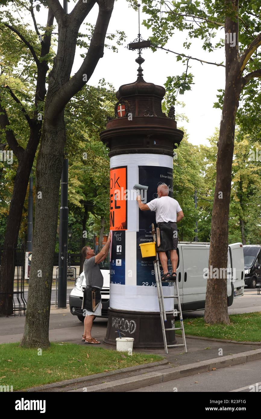 Gli uomini incollando annunci su pannelli pubblicitari Vienna, Austria Foto Stock